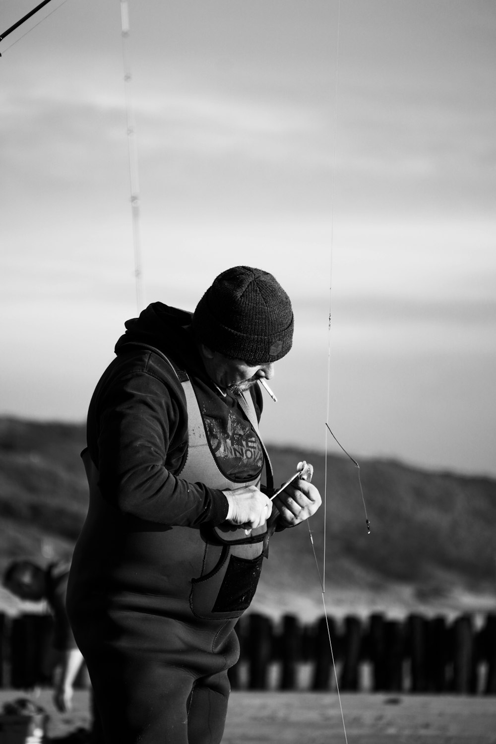 homme en veste noire et bonnet en tricot noir tenant une canne à pêche