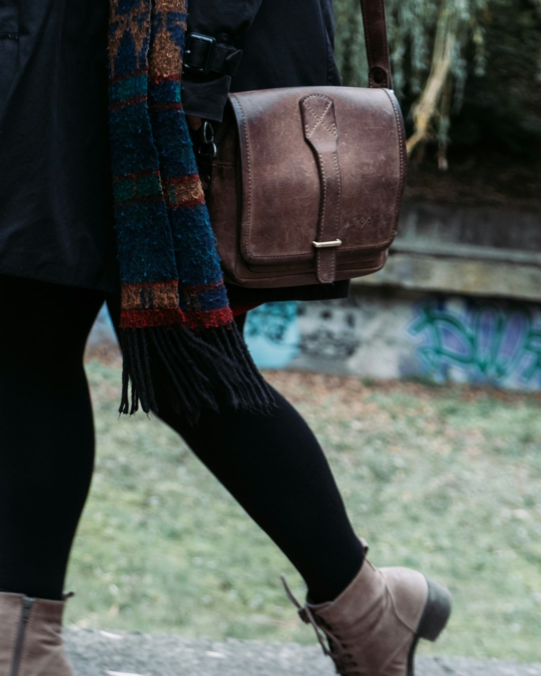 woman in black pants and brown leather sling bag