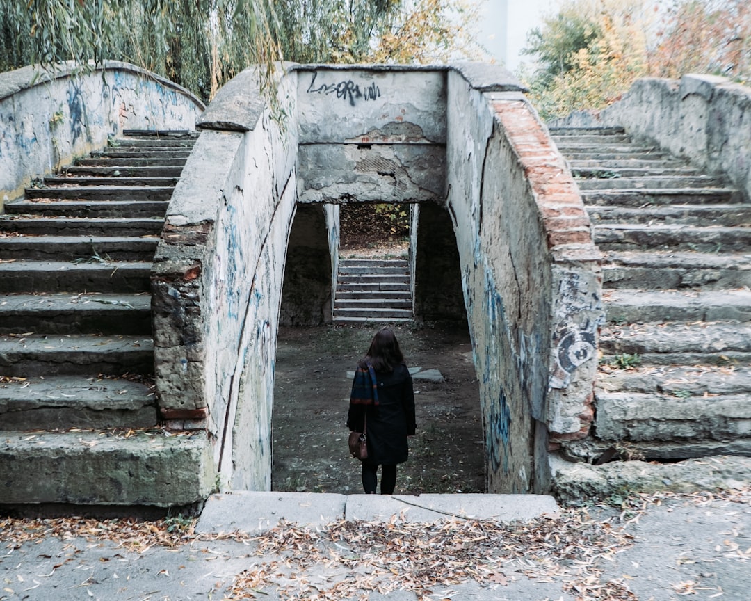 person in black jacket walking on gray concrete tunnel during daytime