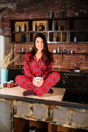woman in red and white plaid coat sitting on brown wooden table