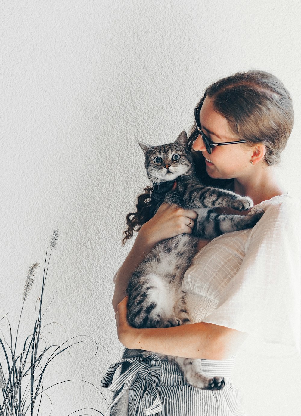 woman in white shirt holding black and white cat