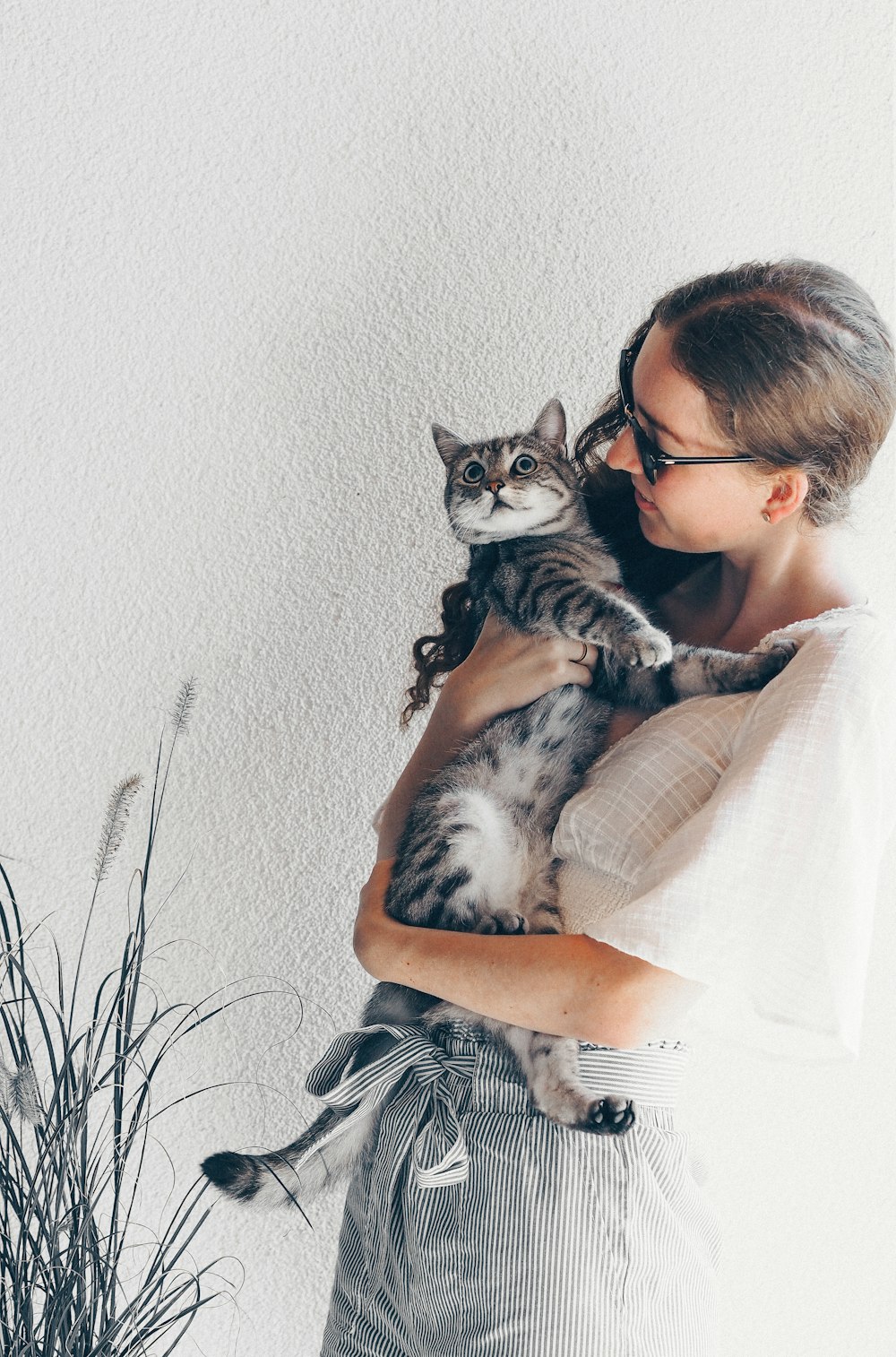 Mujer con camisa de rayas blancas y negras sosteniendo un gato atigrado plateado