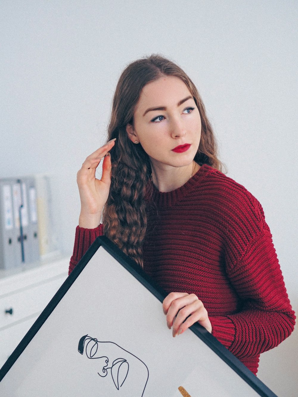 woman in red sweater holding black tablet computer