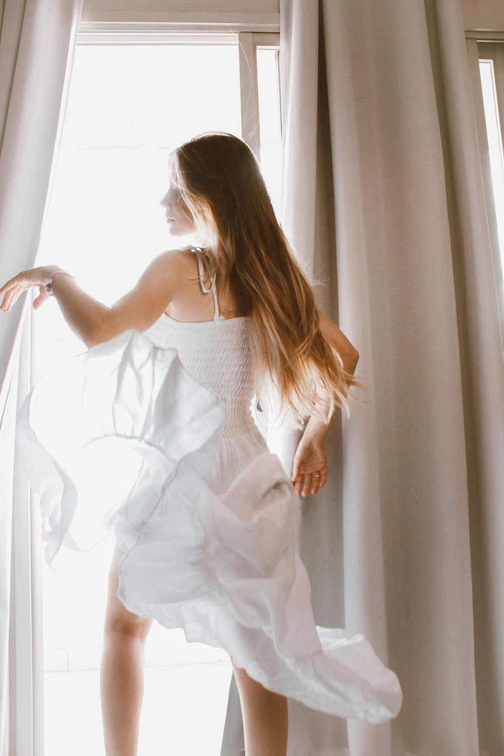 woman in white dress standing near window