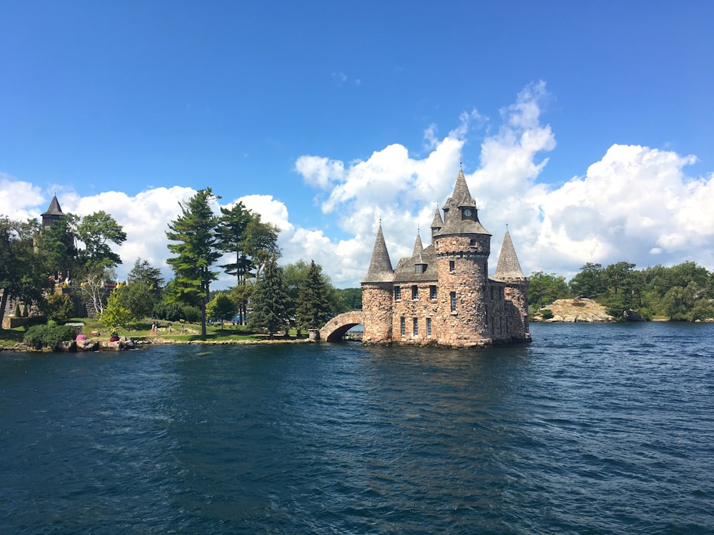 Castello di cemento marrone vicino allo specchio d'acqua sotto il cielo blu durante il giorno