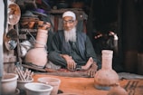 man in gray long sleeve shirt sitting beside brown clay pots