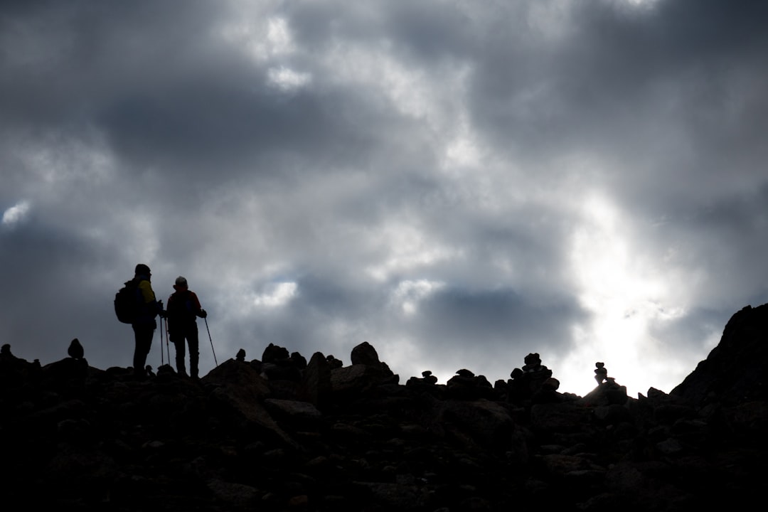 people standing on rocky ground under cloudy sky during daytime