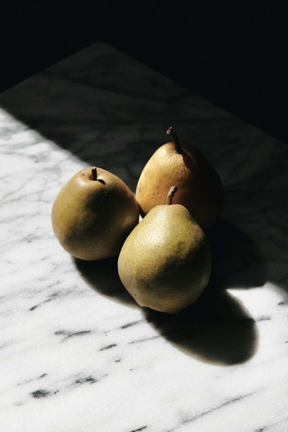 three yellow round fruits on white textile