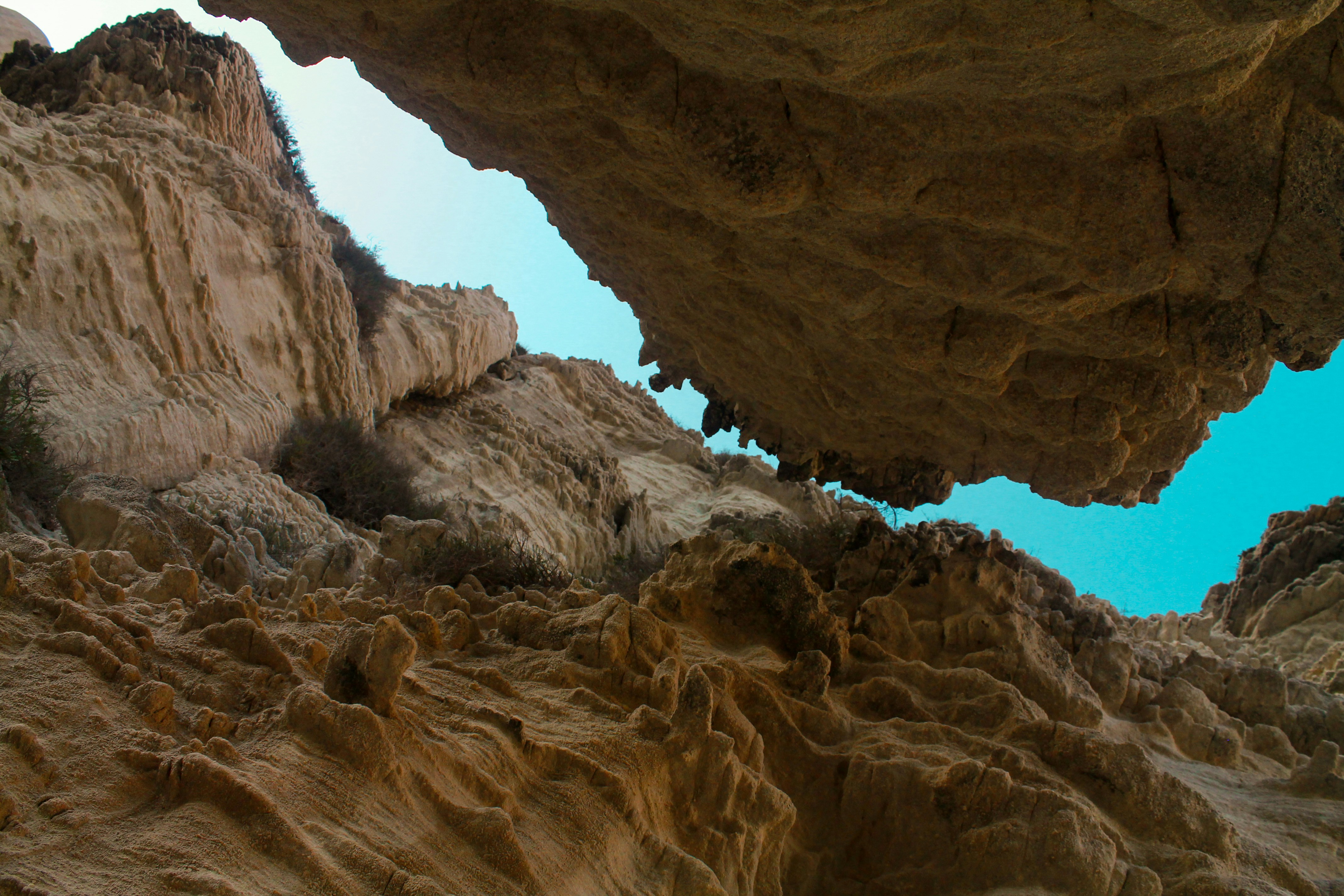 person in blue shirt and blue denim jeans standing on brown rock formation during daytime