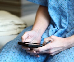 person in blue and white checkered button up shirt holding black smartphone