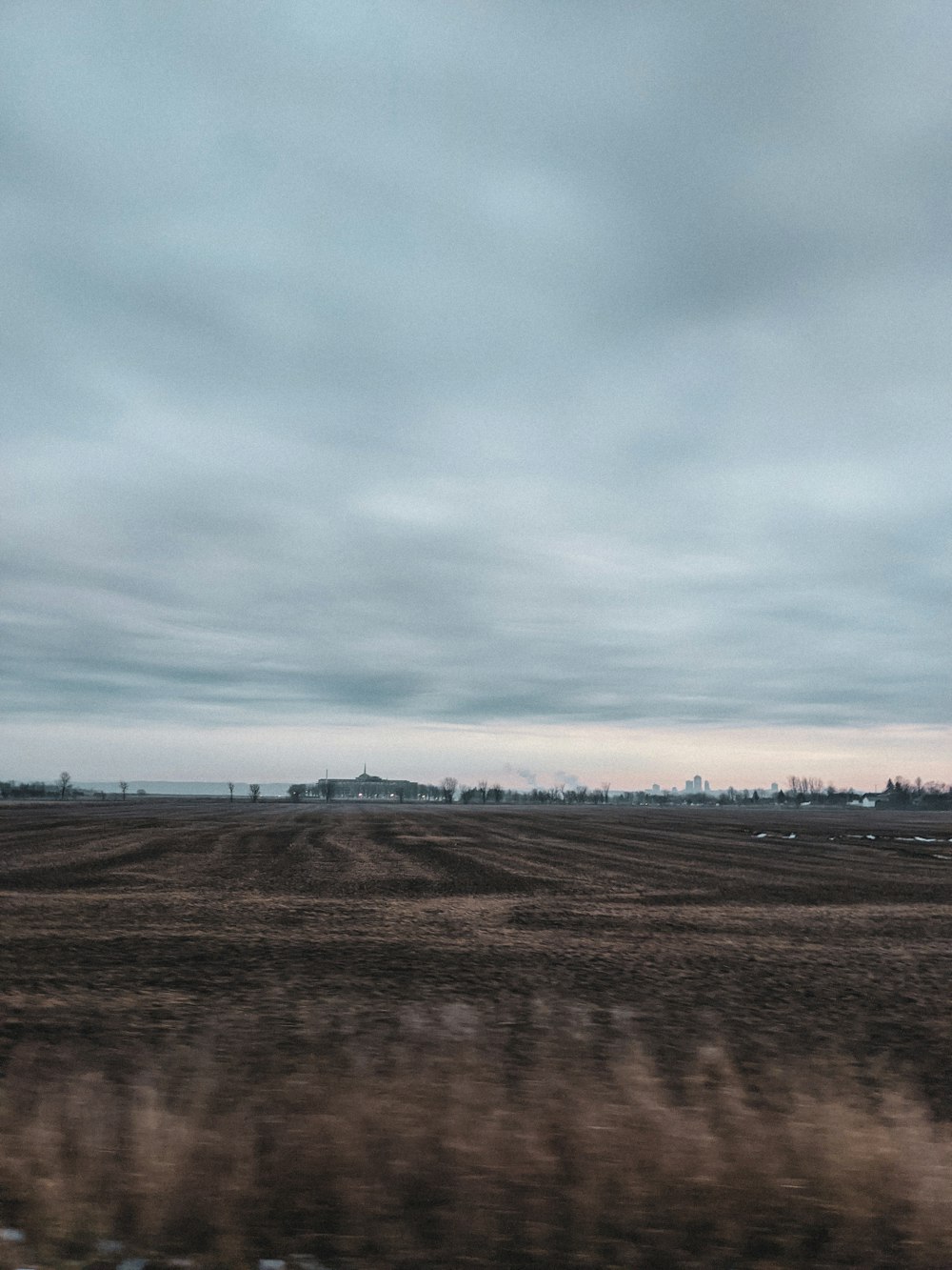 brown field under white clouds during daytime