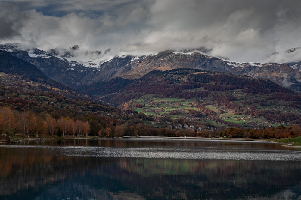 brown and green mountains near lake under white clouds during daytime