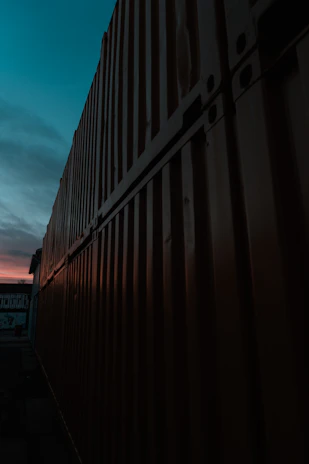 A refrigerated container being loaded onto a trailer at dusk, with warm lighting.