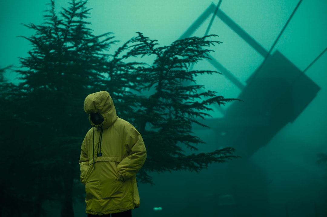 man in yellow jacket standing near green plant