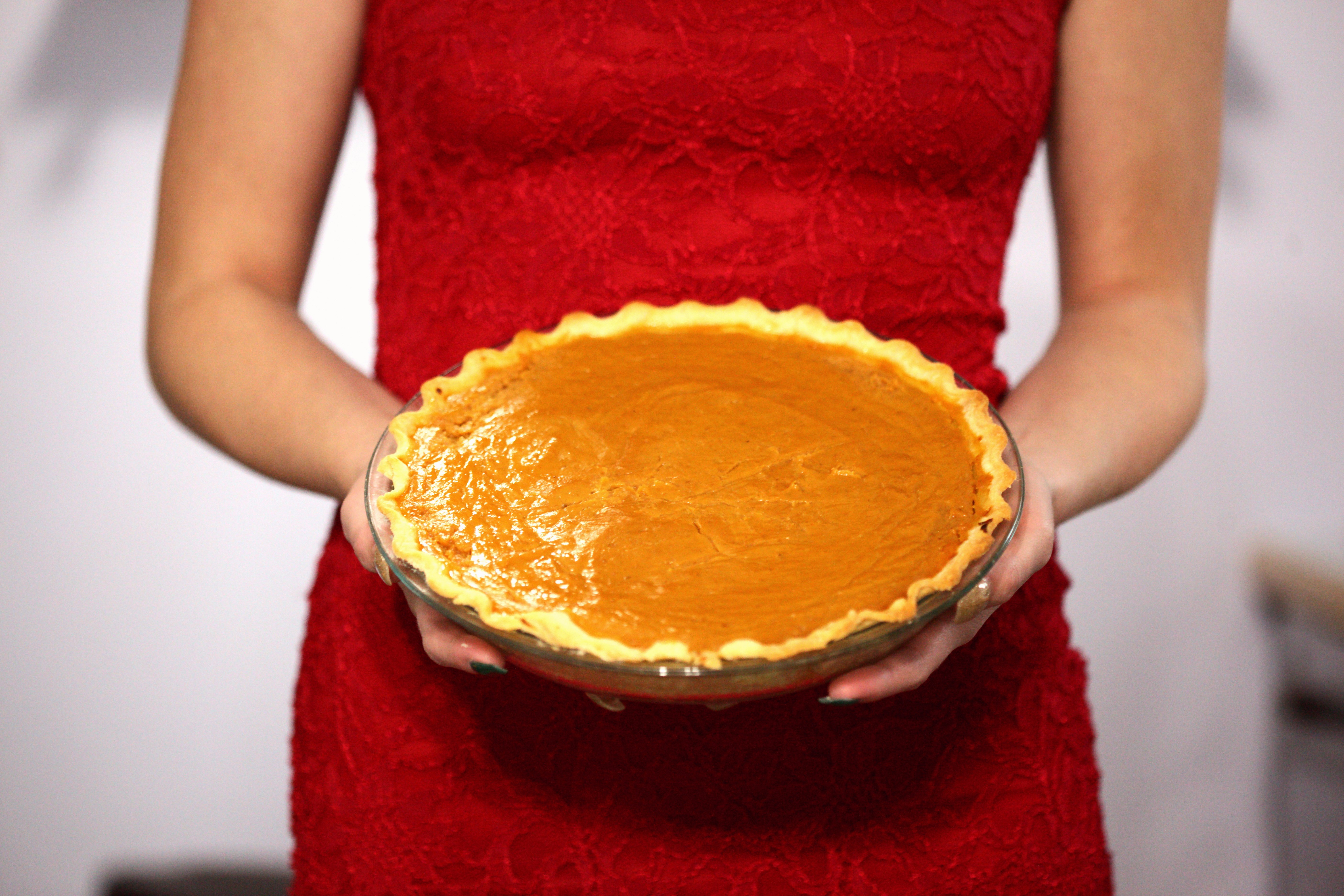 woman in red sleeveless dress holding pie