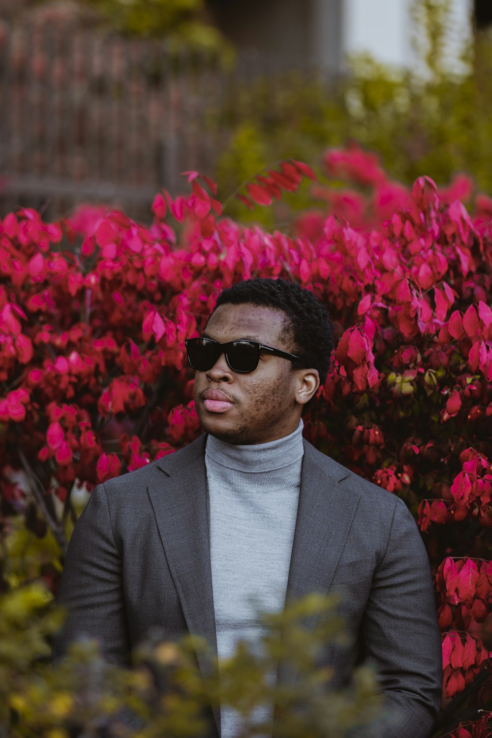 man in black suit standing near red flowers