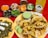 A colorful spread of Mexican food featuring several tacos filled with seasoned meat and pineapple on a yellow plate. Accompanying the tacos are lime wedges and a green sauce. Surrounding the main dish are bowls containing various garnishes such as chopped cilantro, cucumbers, sliced onions, and several sauces of different colors. A plate with sliced cactus and cheese is also visible. In the background, there is a bottle of pineapple-flavored soda.