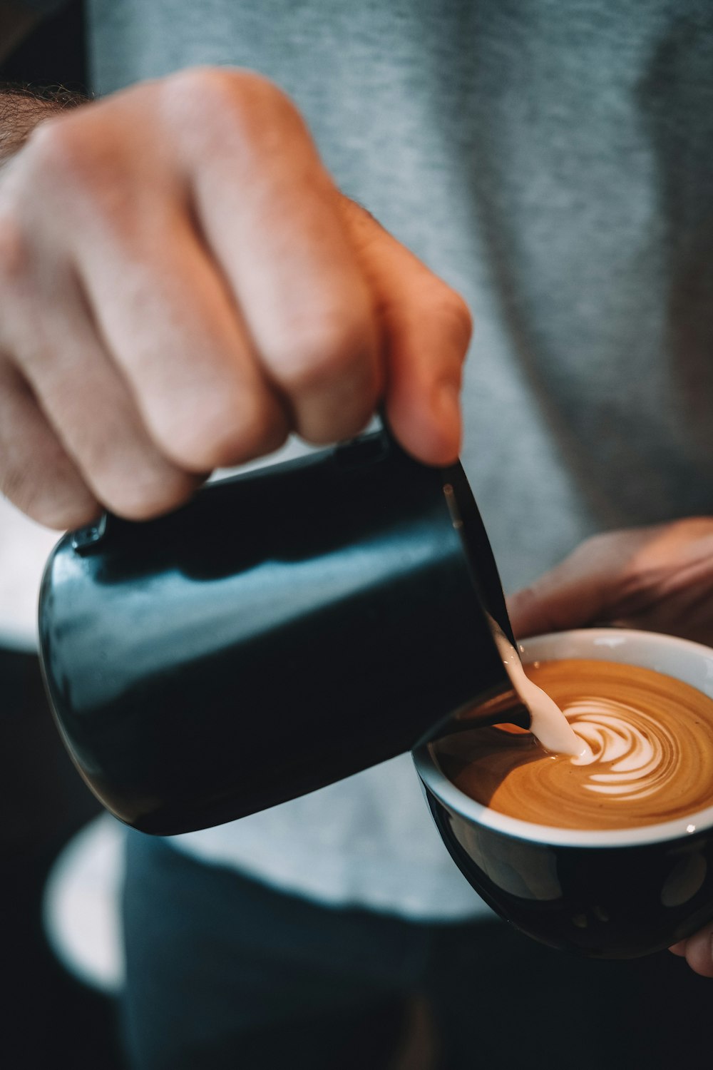 person pouring coffee on black ceramic mug