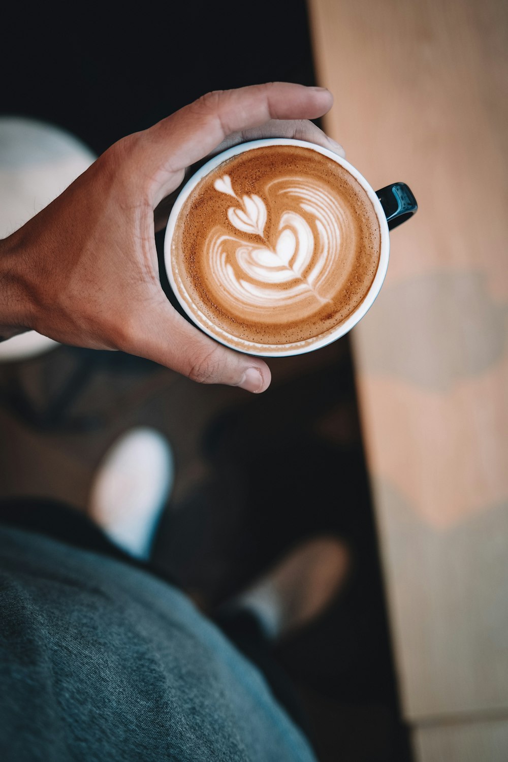 person holding brown ceramic mug with brown and white liquid