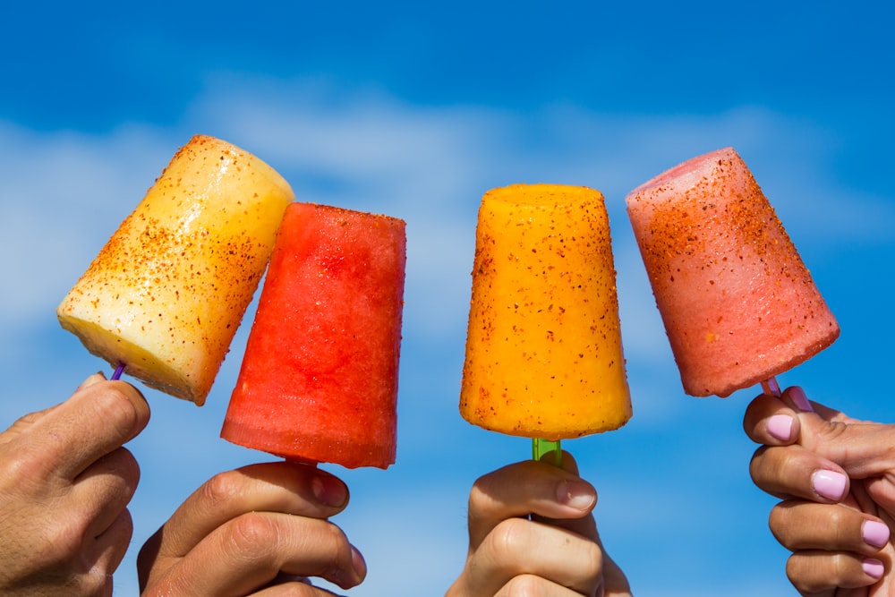 person holding orange ice pop