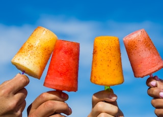 person holding orange ice pop