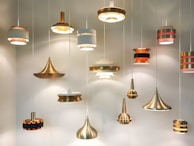 Group of metal pendant lights hanging at different heights, showcasing varied finishes and craftsmanship.