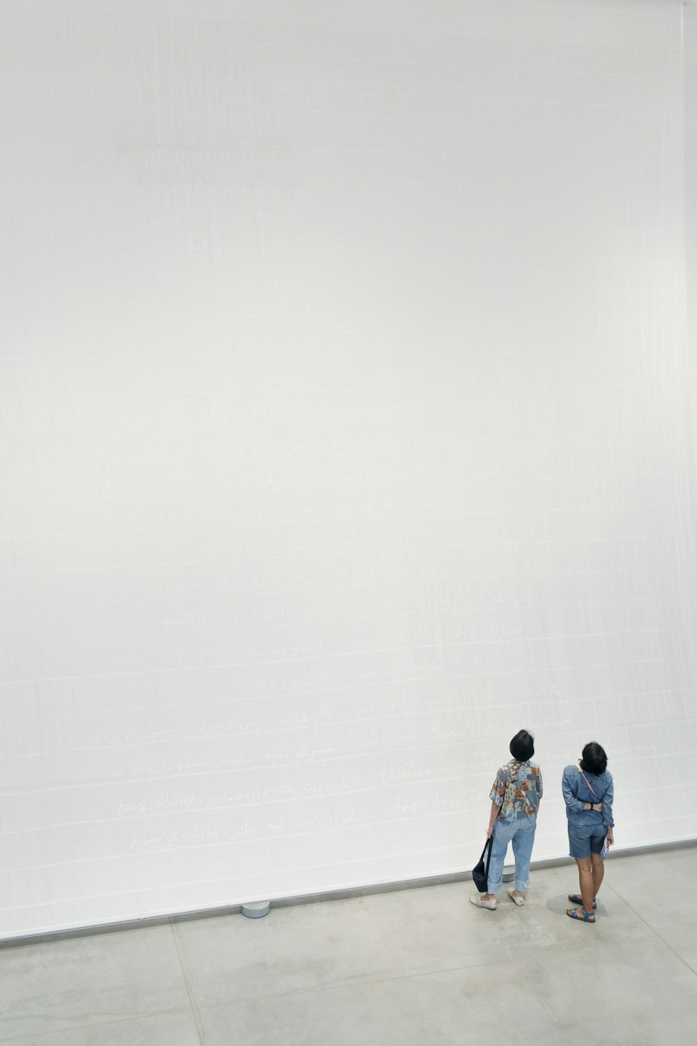 2 women standing looking at a white wall