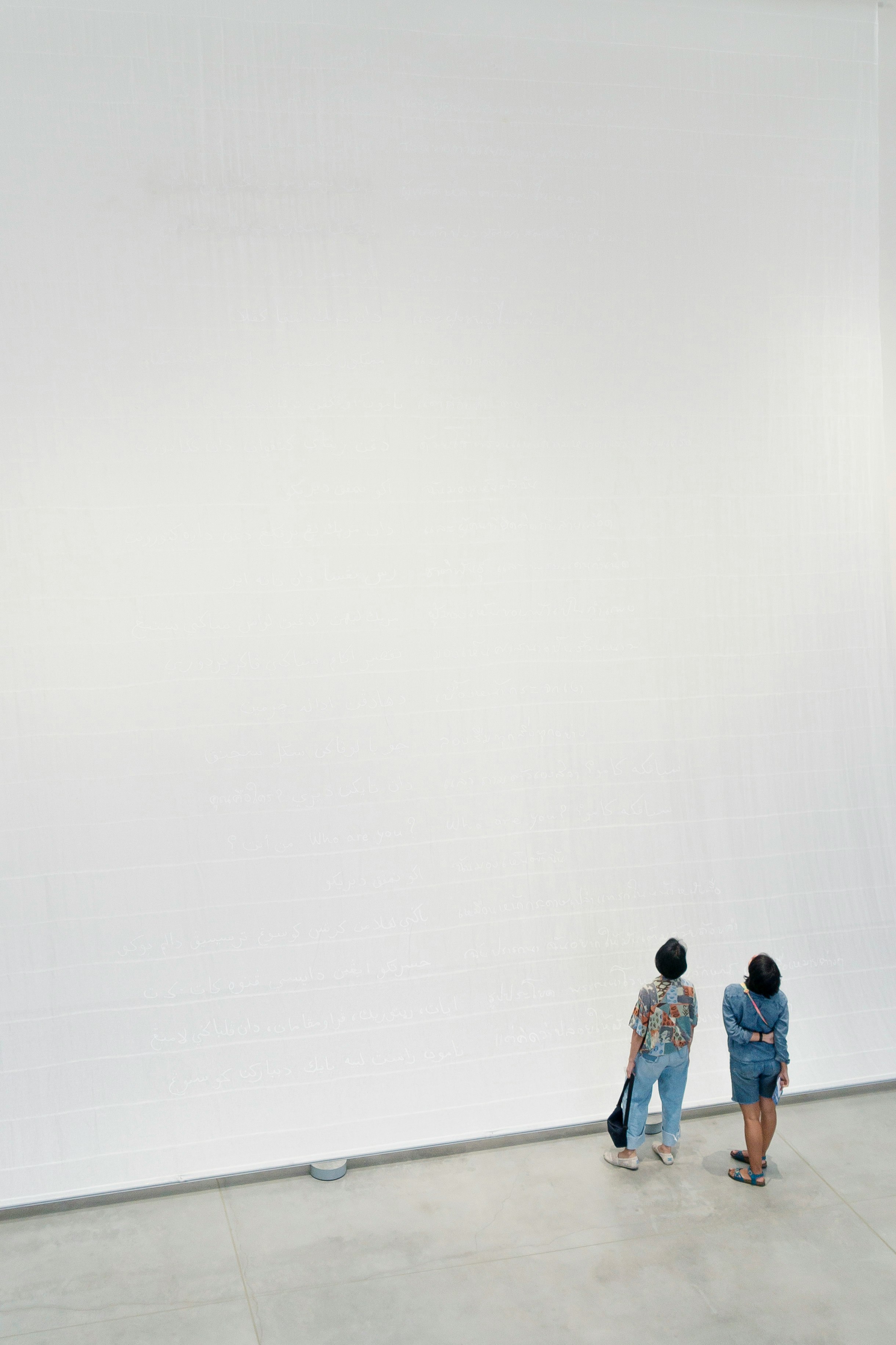 2 women standing looking at a white wall