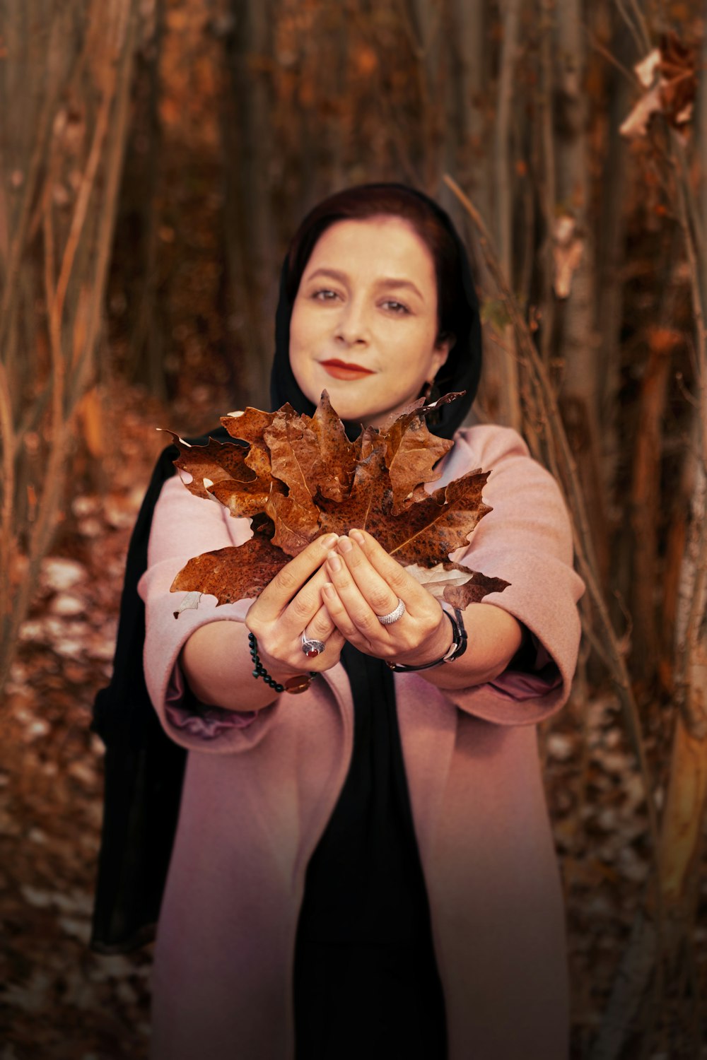 Mujer con camisa marrón de manga larga sosteniendo hojas secas