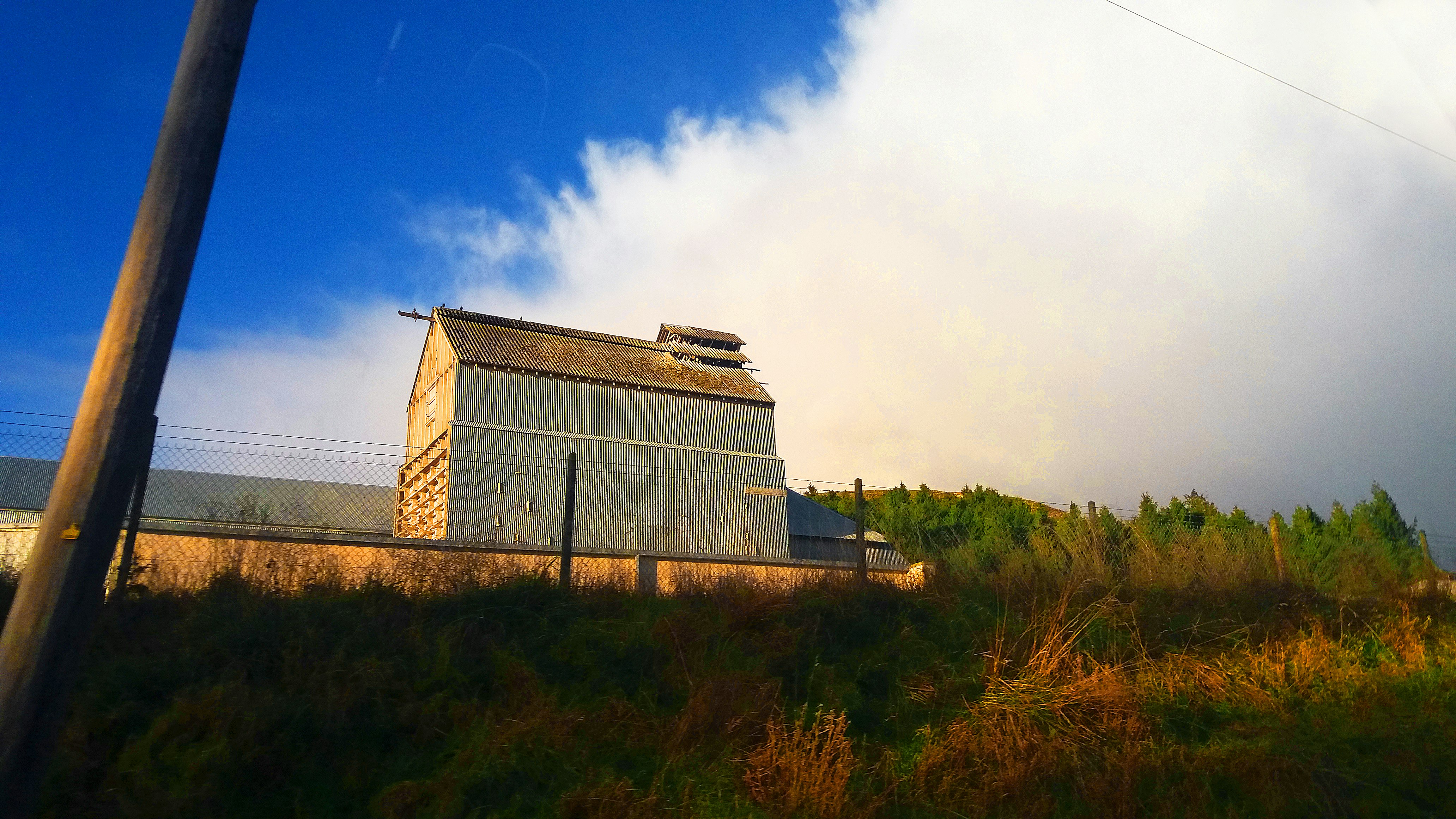 gray concrete building on green grass field under blue sky during daytime