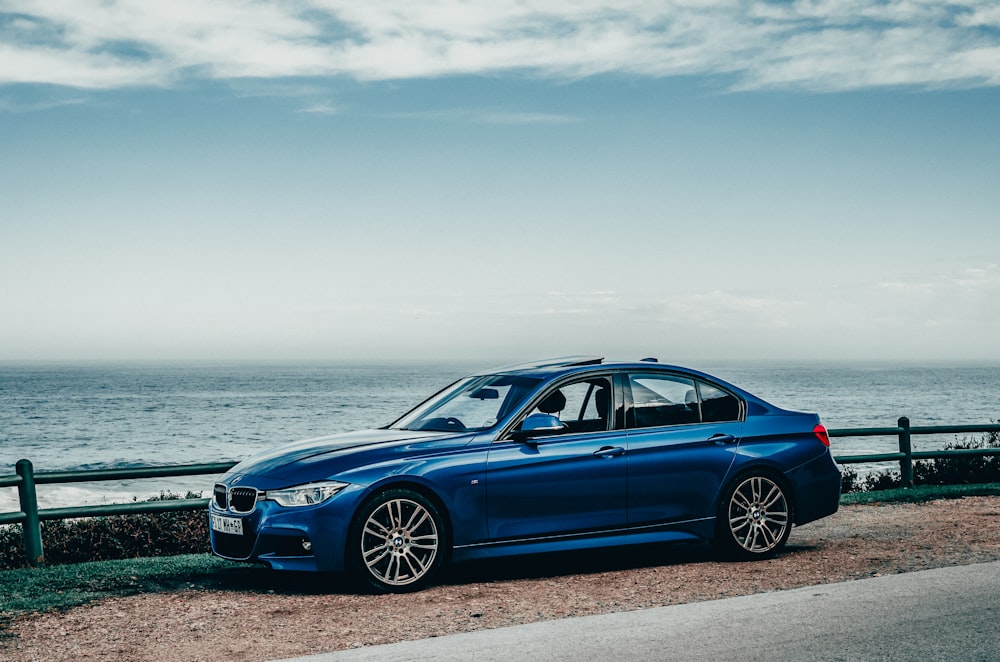 BMW M 3 Coupé azul aparcado en la orilla del mar durante el día