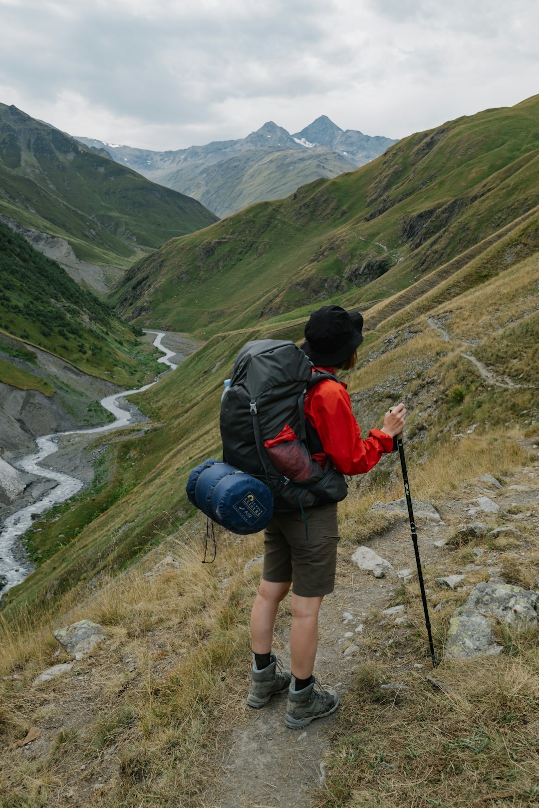 man in black and red backpack and black backpack standing on green grass field during daytime