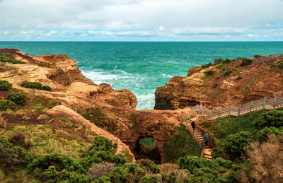 A scenic coastal trail winding along rugged cliffs with ocean waves crashing below.
