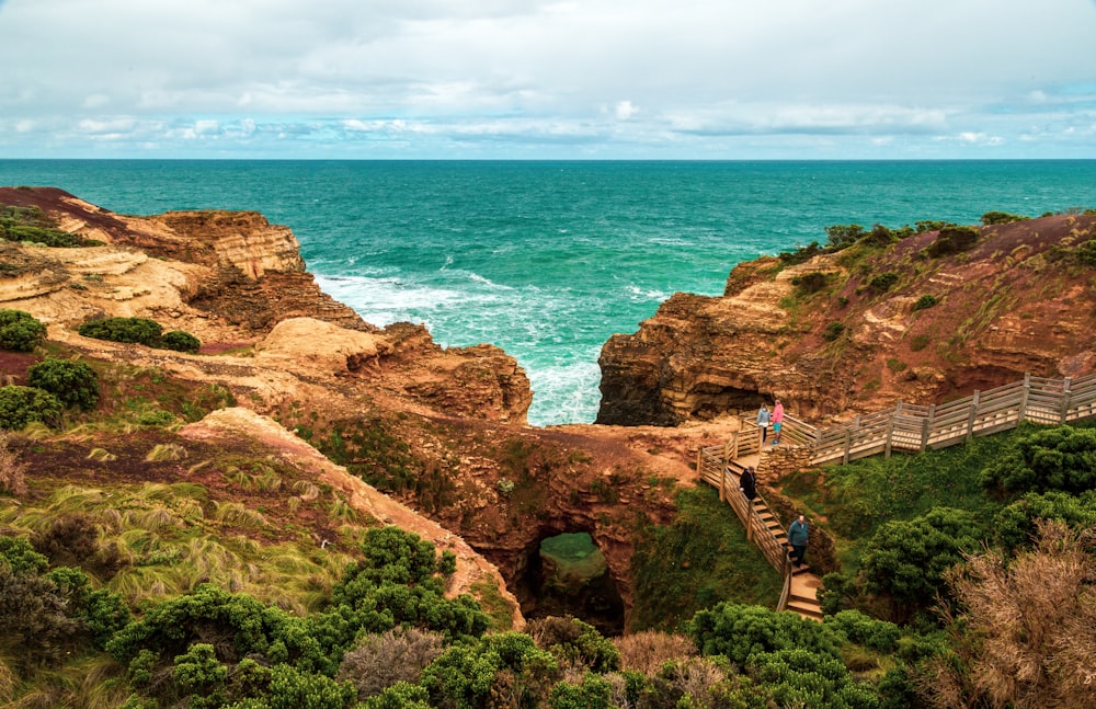 people walking on brown rocky mountain near sea during daytime