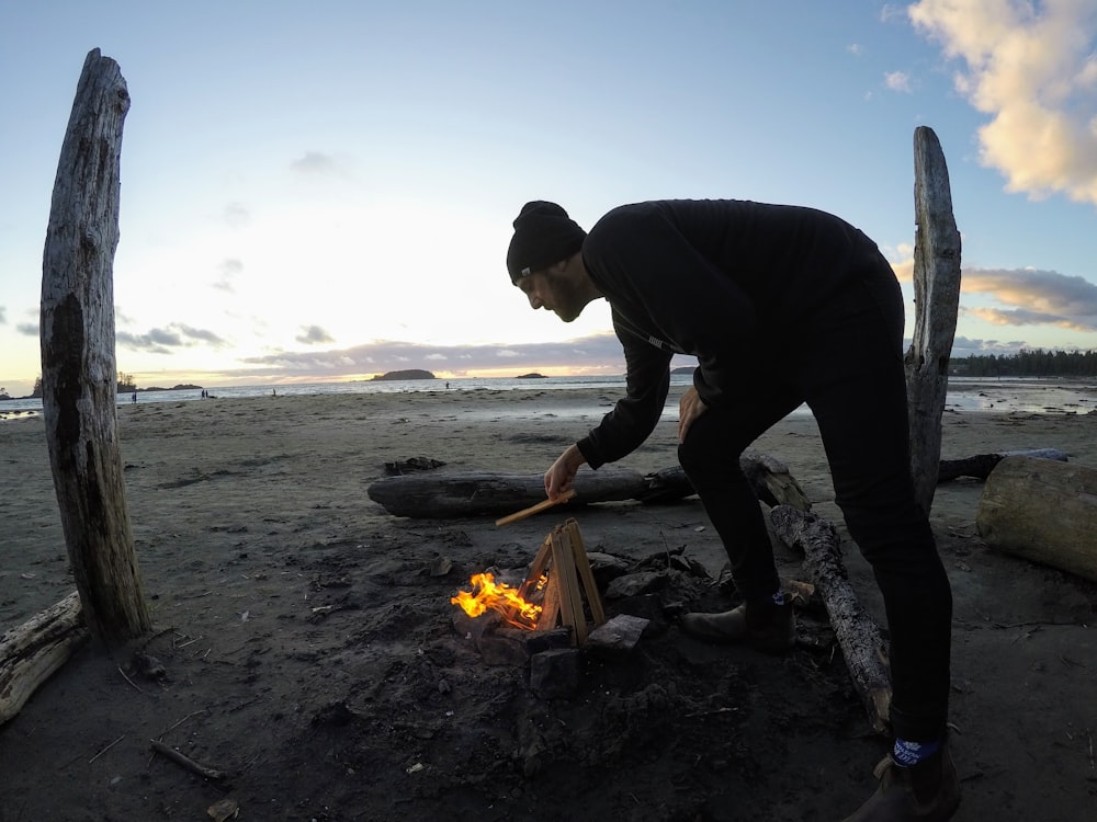 man in black long sleeve shirt and black pants holding fire