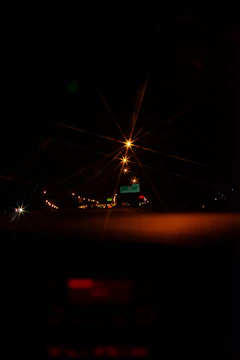 A nighttime highway stretching into the distance, illuminated by golden streetlights with a sleek car dashboard glowing softly.