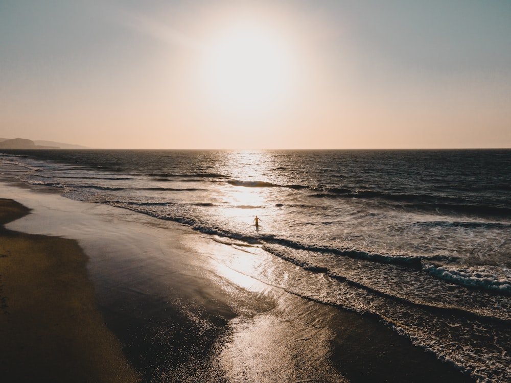 sea waves crashing on shore during sunset