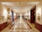 Elegant hotel lobby corridor bathed in warm golden light with smooth glass surfaces.
