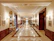 Elegant hotel lobby corridor bathed in warm golden light with smooth glass surfaces.