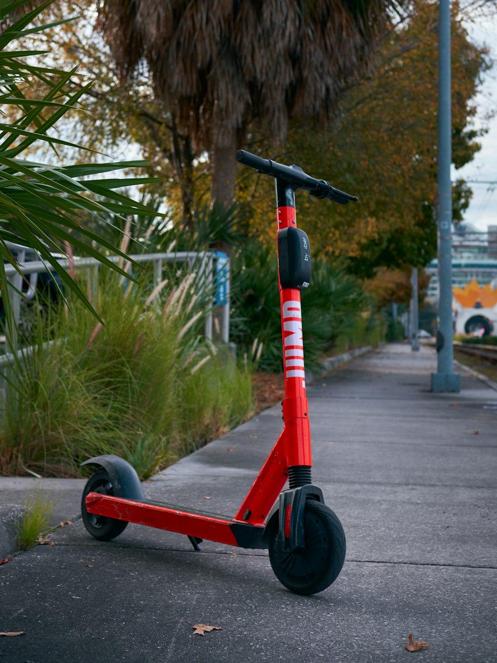 trottinette rouge et noire sur une route en béton gris pendant la journée