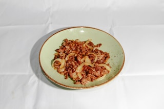 brown food on white and green ceramic bowl