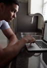 man in gray t-shirt using macbook pro