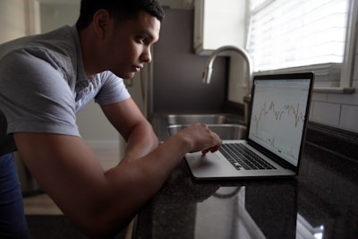 A focused investor analyzing market charts on a laptop during a webinar.