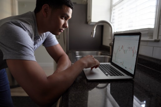 A focused trader analyzing forex charts on multiple screens in a cozy home office.