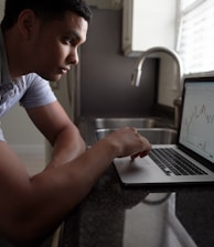 man in gray t-shirt using macbook pro