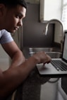 man in gray t-shirt using macbook pro