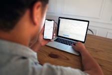man in gray hoodie holding black smartphone
