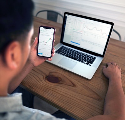 person holding iphone 6 near macbook pro