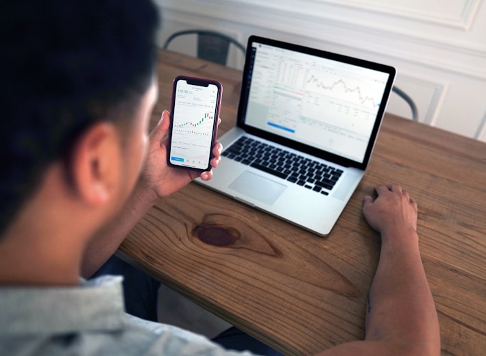 person holding iphone 6 near macbook pro