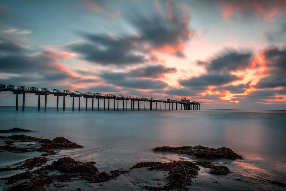 brown wooden dock on body of water under cloudy sky during daytime